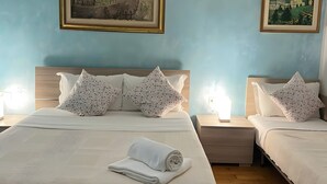 A double bed with a rolled white towel, two nightstands with lamps, and two framed paintings on the wall. - 'Venice' Apartment with Wi-Fi and Air Conditioning (Venezia)