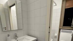 A modern bathroom with a white sink, dark vanity, and a mirror. - 'Venice' Apartment with Wi-Fi and Air Conditioning (Venezia)