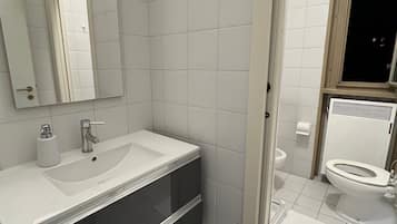Ein modernes Badezimmer mit einem weißen Waschbecken, einer dunklen Waschtischunterschrank und einem Spiegel.
