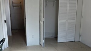 Una habitación con suelo de baldosas, una puerta blanca y un armario con puertas correderas.