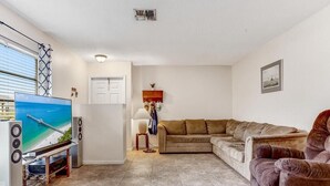 Una sala de estar con televisión, sofá y una mesita.