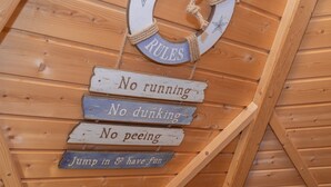 Un mur en bois sur lequel on peut lire les panneaux suivants : « Il est interdit de courir », « Il est interdit de faire des dunks », « Il est interdit de faire pipi » et « Sautez et amusez-vous ! ».