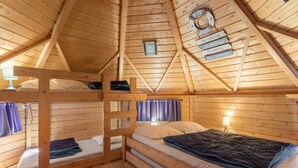 Une cabane en bois avec des lits superposés, une horloge au plafond et un panneau affichant les règles.