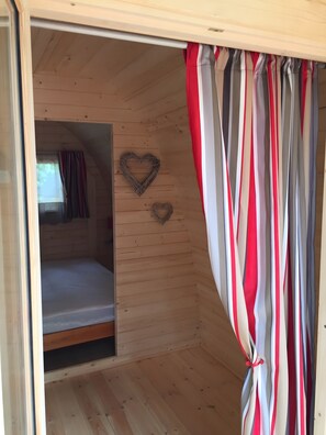 Een houten interieur met een bed, gestreepte gordijnen en een hartvormige decoratie.