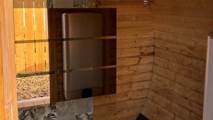 A small, compact room with wooden walls, a metal-framed window, a black mat, and a metal appliance. - Barrel Orange Apartment with Mountain View, Private Terrace & Air Conditioning (Saint André)