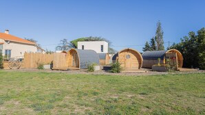 A row of wooden dome-shaped cabins with a white building in the background. - Barrel Violet Apartment with Mountain View, Wi-Fi, and Air Conditioning (Saint-André)