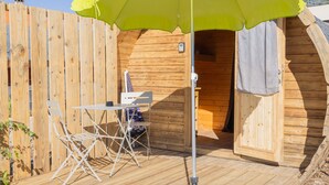 A wooden deck with a table and chairs, a yellow umbrella, and a wooden cabin structure. - Barrel Violet Apartment with Mountain View, Wi-Fi, and Air Conditioning (Saint-André)