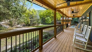 A wooden deck with a railing, ceiling fans, and outdoor seating.