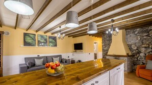 A kitchen with a wooden countertop, a fruit bowl, a stone wall, and a television. - Vacation Home 'La Era' with Mountain View, Private Pool and Wi-Fi (Adeje)