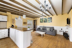 A spacious living area with a kitchen, wooden beams, a grey sofa, and a chandelier. - Vacation Home 'La Era' with Mountain View, Private Pool and Wi-Fi (Adeje)