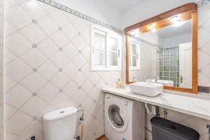 A bathroom with a washing machine, toilet, and sink.