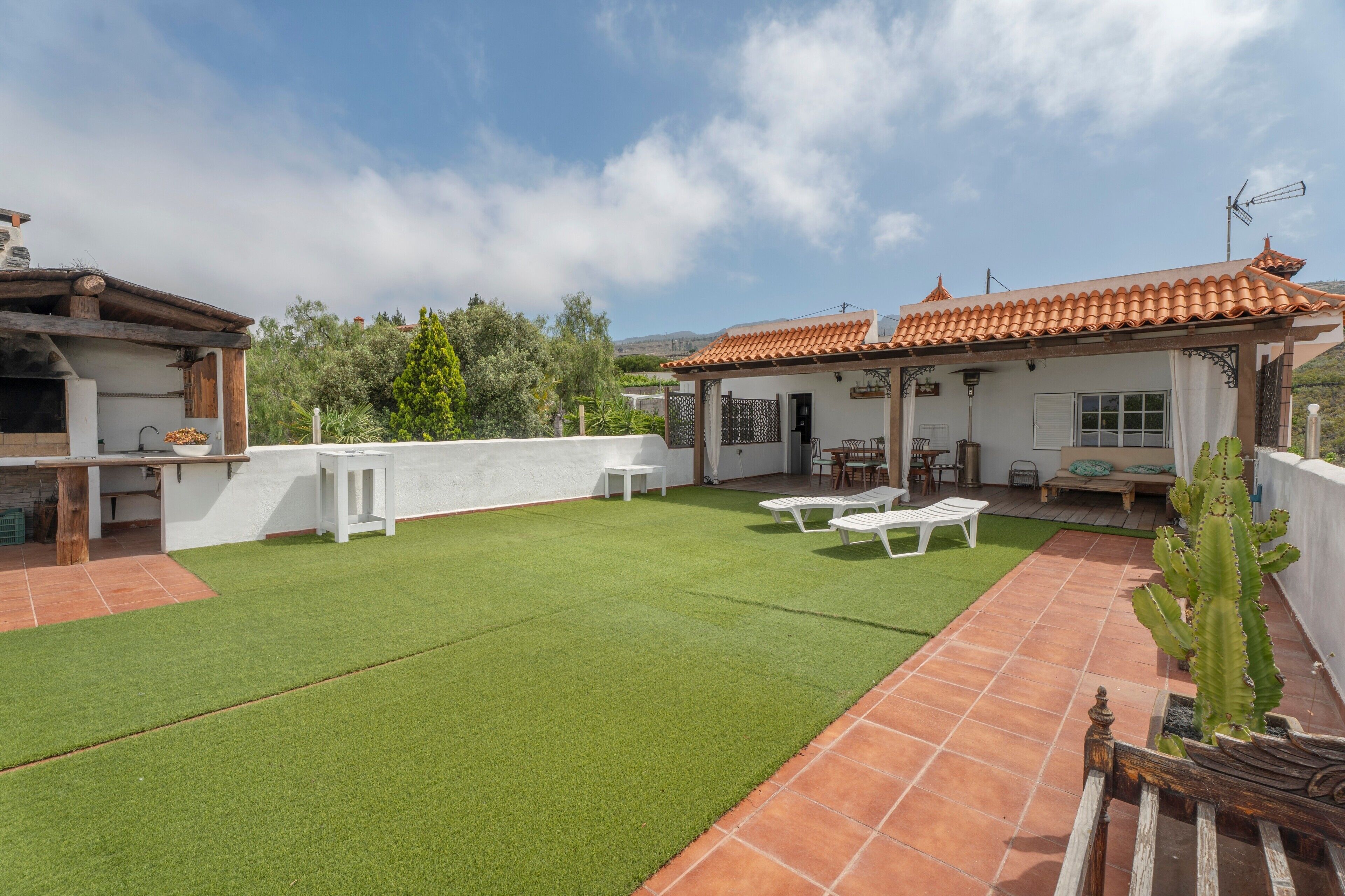 A patio with artificial grass, a white table, and a white chair.