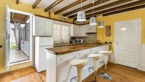 A kitchen with wooden beams, white cabinets, a wooden countertop, and three white bar stools. - Vacation Home 'La Era' with Mountain View, Private Pool and Wi-Fi (Adeje)