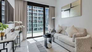 A modern living room with a sofa, a coffee table, a TV, and a large window with curtains.