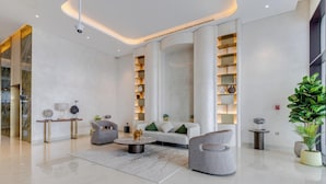 A modern hotel lobby with a marble floor, a round coffee table, a sofa, and a large potted plant.