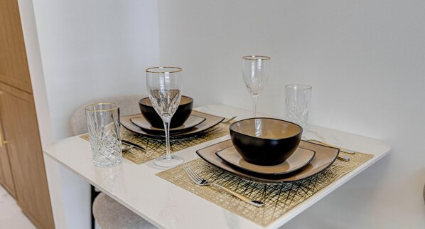 A dining table set with black and gold plates, clear glasses, and a woven placemat. - GLOBALSTAY Azizi Riviera 67 (Dubai)