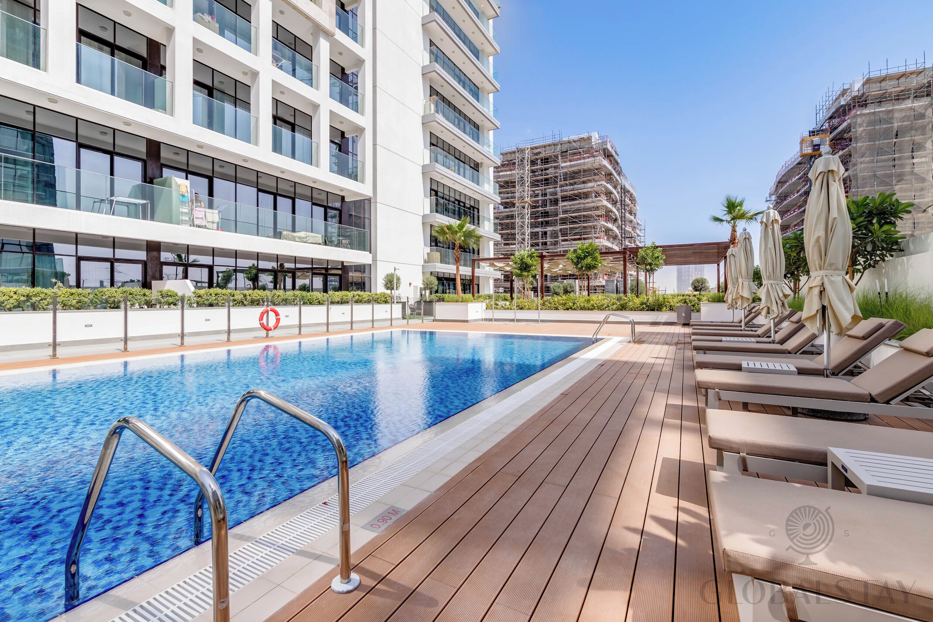 Una piscina al aire libre, sombrillas, sillones reclinables de piscina