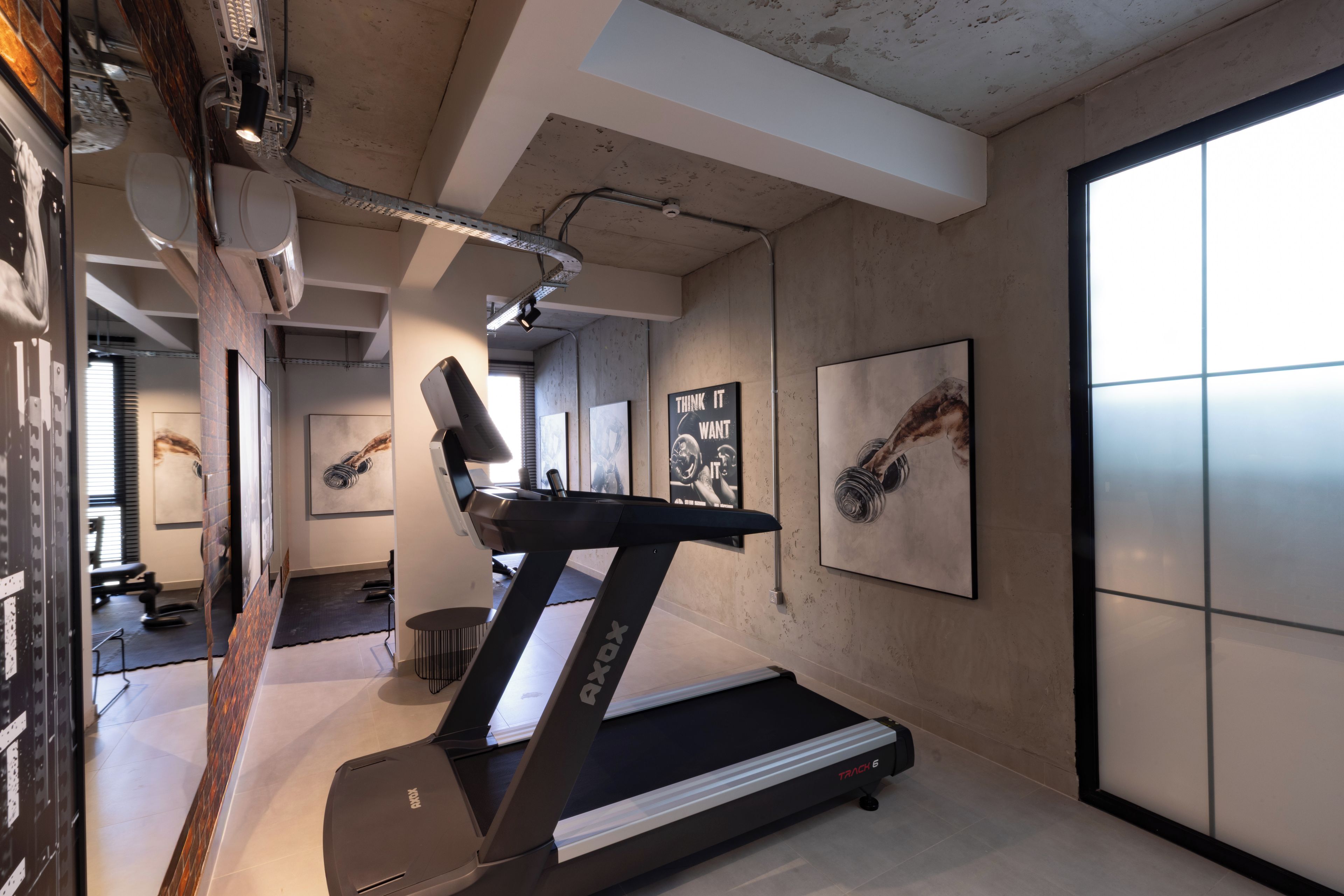 Ein modernes Fitnessstudio mit Laufband, Trainingsgeräten und motivierenden Postern an den Wänden.