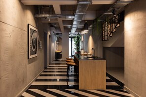 A modern interior with a central island, black and white striped flooring, and exposed ductwork on the ceiling. - C LIVING 3 - ALMALQA (Riyadh)