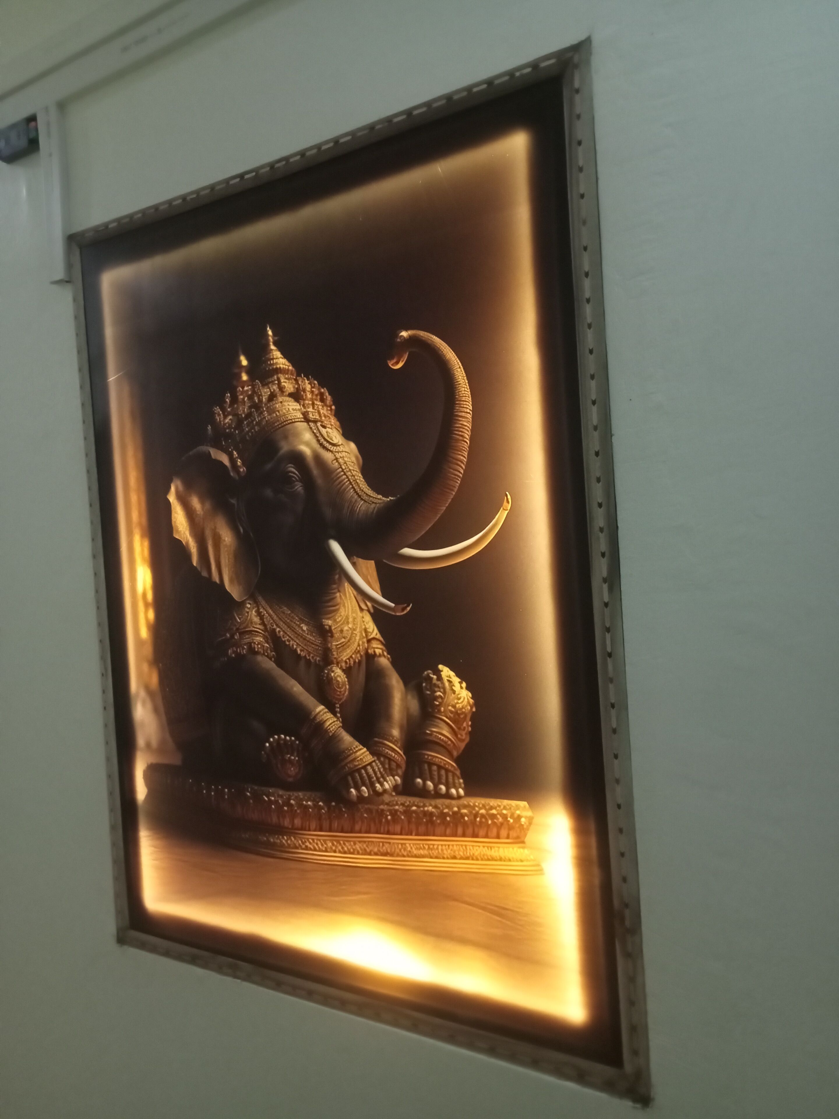 A framed statue of an elephant deity with intricate jewelry and a seated posture.