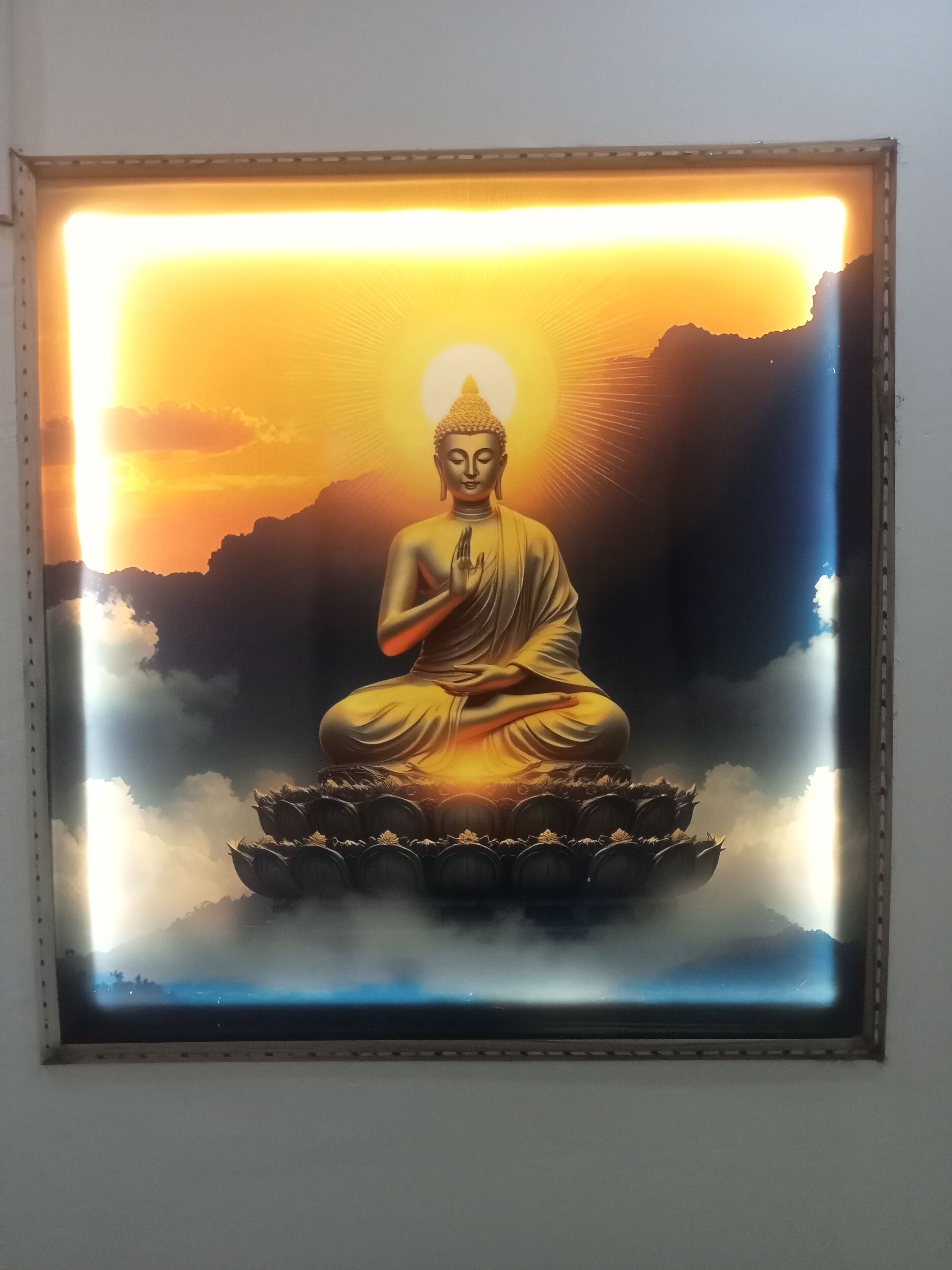 A framed Buddha statue with a sunset background.