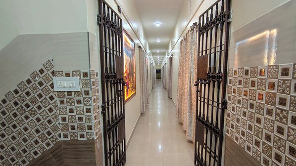 A corridor with patterned tile walls, metal gates, and a tiled floor. - ASHOK NANDINI GUEST HOUSE (Bhubaneshwar)