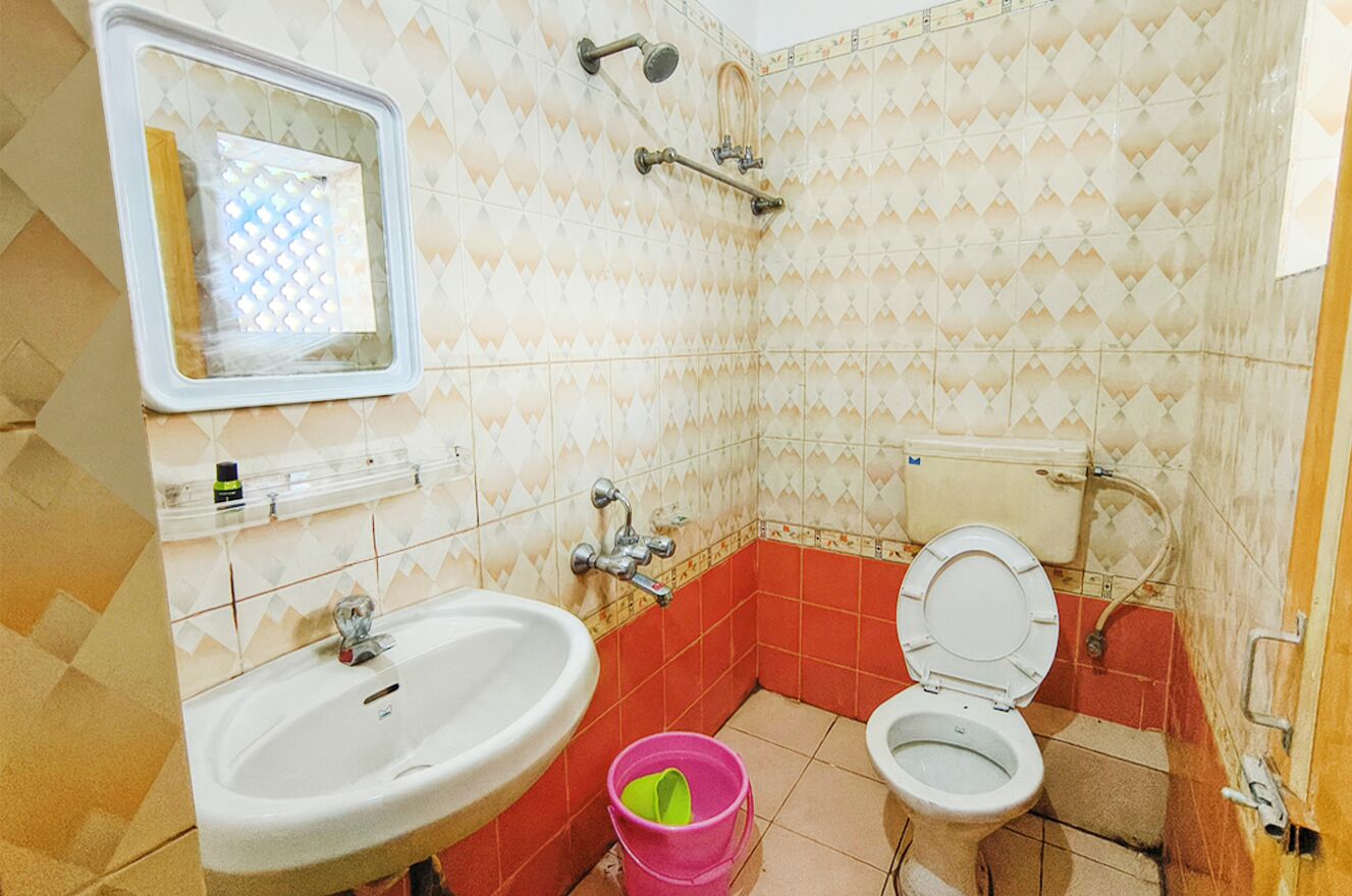 Et badeværelse med vask, toilet og bruser.