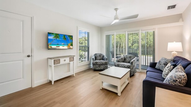 A living room with a TV, a ceiling fan, a sofa, and a coffee table.