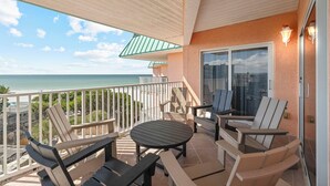A balcony with a table and chairs, a glass door, and a view of the ocean. - Top Floor 3BR | Panoramic Gulf & Seabird Sanctuary | Pool, Hot Tub, Sleeps 11 (Indian Shores)