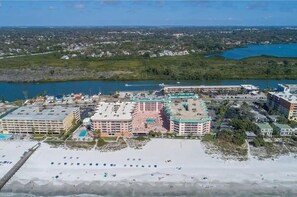 Un hotel costero con varias edificaciones, una playa y una masa de agua al fondo.