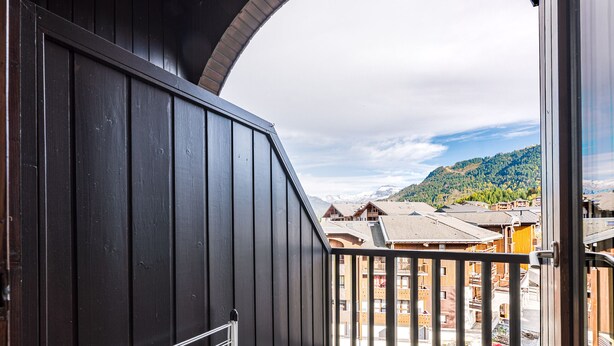 Un balcon donnant sur un paysage montagneux et un bâtiment en bois.