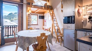 Une pièce chaleureuse comprenant une table à manger, des chaises, un coin cuisine et une échelle en bois.