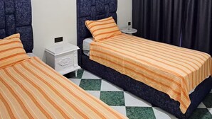 Ein Hotelzimmer mit zwei Betten, einer Deckenleuchte, einem Nachttisch und einem Schachbrettmuster-Boden.