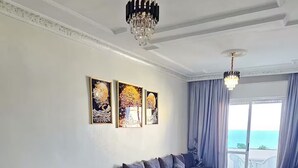 Ein Essbereich mit kariertem Boden, einem Tisch mit Blumenvase und einer Couch mit Meerblick.