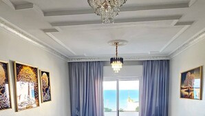 Ein geräumiger Raum mit kariertem Boden, zwei Sofas, einer Kristallleuchtre und Kunstwerken an den Wänden.