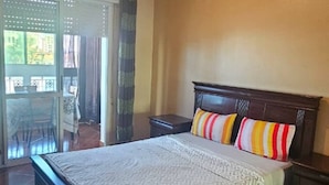 A bedroom with a large bed, a wooden headboard, and a ceiling light. - Brise d’Océan Tanger (Tangier)