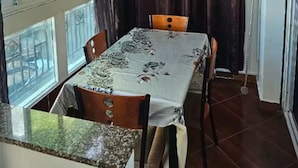 A dining area with a table set for four, a window with curtains, and a view of buildings outside. - Brise d’Océan Tanger (Tangier)