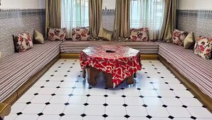 A spacious living room with a central coffee table, patterned sofas, and a tiled floor.