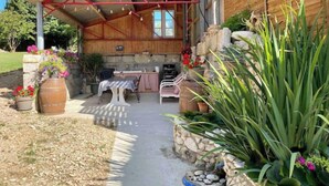 Un patio cubierto con mesa y sillas, una pared de piedra y plantas en macetas.