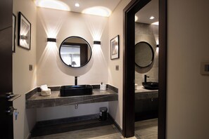 A modern bathroom with a black sink, two mirrors, and framed pictures on the wall. - Luxury Rooms at Pyramids Gem (Giza)