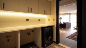 A modern kitchen with built-in appliances, a washing machine, and a dining area visible through an open door. - Luxury Rooms at Pyramids Gem (Giza)