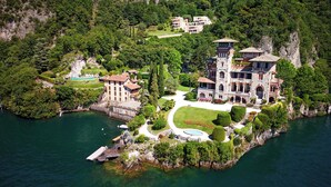 Un vaste manoir historique comprenant plusieurs bâtiments, une piscine et un quai.