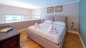 Een slaapkamer met een groot bed, een nachtkastje, een bureau en een raam met uitzicht.