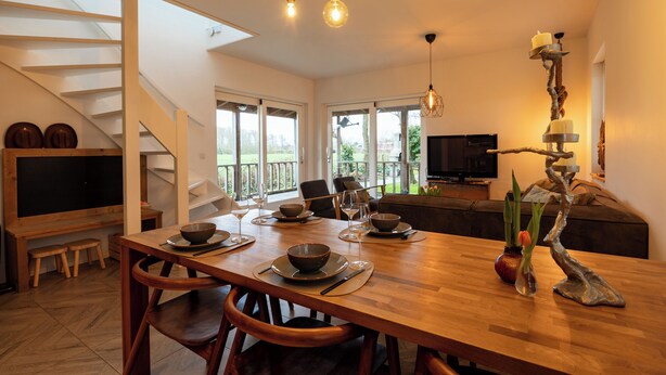 Un comedor moderno con una mesa de madera, sillas y un televisor al fondo.