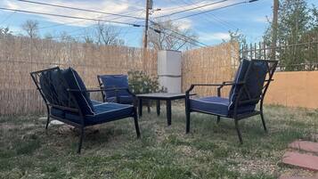 An outdoor seating area with two chairs and a table, surrounded by a wooden fence and power lines.