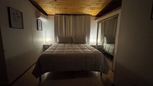 A bedroom with a bed, bedside lamps, a mirror, and a ceiling light fixture. - Charming 2-bedroom Guest house in Santa Fe with AC (Santa Fe)
