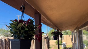 A covered outdoor area with hanging planters and a wooden fence. - Charming 2-bedroom Guest house in Santa Fe with AC (Santa Fe)
