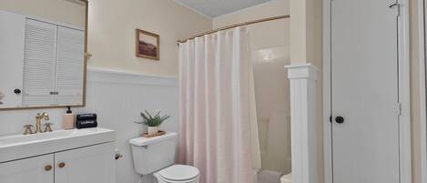 A bathroom with a toilet, sink, mirror, and shower curtain.