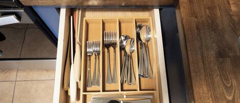 A drawer containing various kitchen utensils including forks, spoons, and knives.