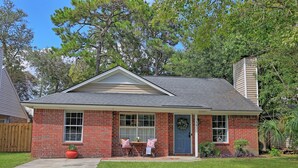A single-story brick house with a front porch, a small garden, and a wooden fence in the background. - New Meets Nostalgic- Cottage Sleeps 8 (Savannah)